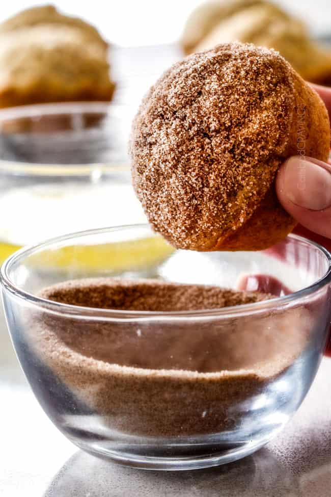 Showing how to make Nutella Stuffed Snickerdoodle Muffins by dipping in sugar and cinnamon.