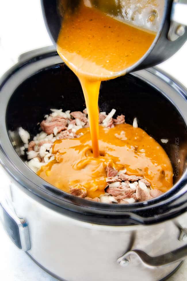 This is by far my family's favorite Slow Cooker Beef Stroganoff recipe! An ultra rich and creamy, amazingly flavorful sauce (without any "cream of" anything!), crazy tender meat all made in the crockpot for a gourmet meal with hardly any effort! I love serving this for holidays like Christmas! Showing how to make Crock Pot Beef Stroganoff Recipe by pouring homemade gravy into slow cooker on top of sliced meat, onions and mushrooms