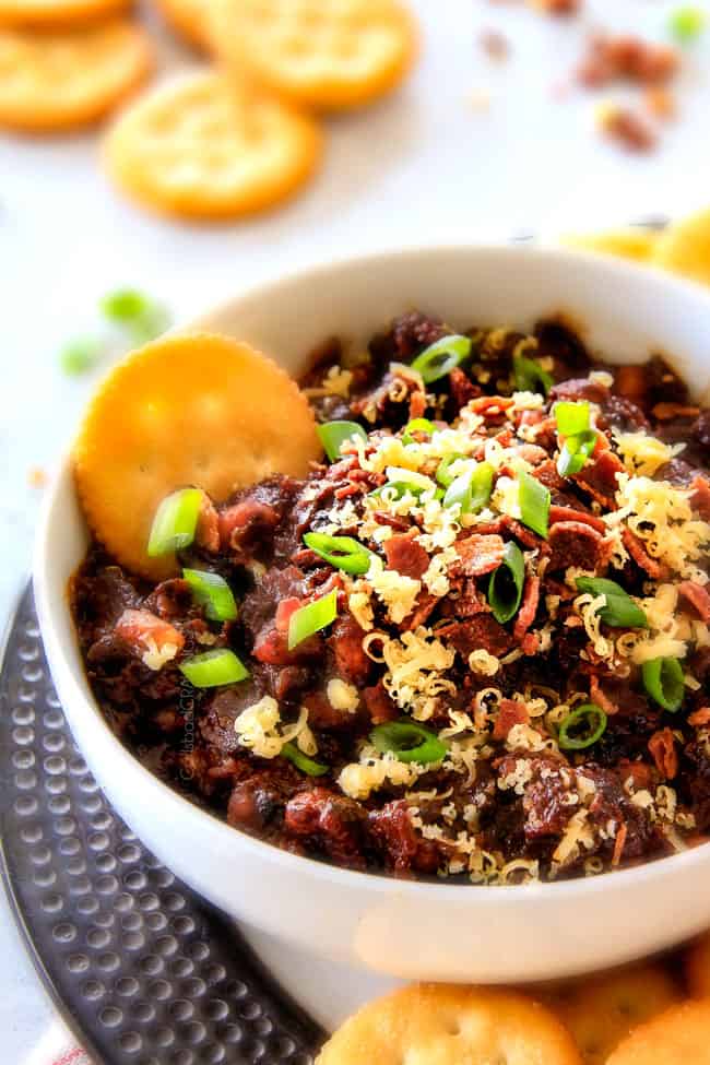 Close up of Boston Baked Bean Dip piled with bacon, cheese, sour cream, green onions.