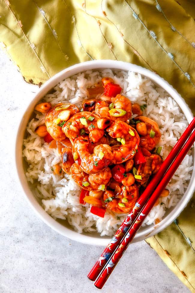 This easy, healthy, Kung Pao Shrimp tastes better than takeout and is on your table in less than 30 minutes! I was licking my plate of the savory spicy sauce! top view of easy Kung Pao Shrimp in a white bowl with red chopsticks