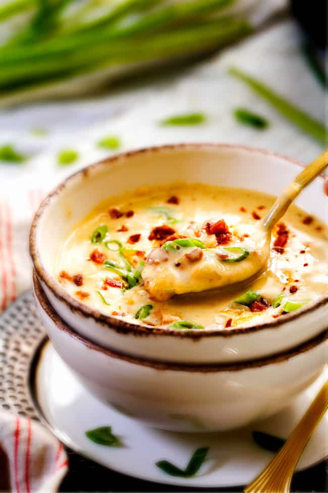 This Skinny Slow Cooker Potato Soup is unbelievably creamy, super flavorful and absolutely the best I've ever tried! and its super easy in the crock pot! far away shot of crockpot potato soup in a bowl with a gold spoon