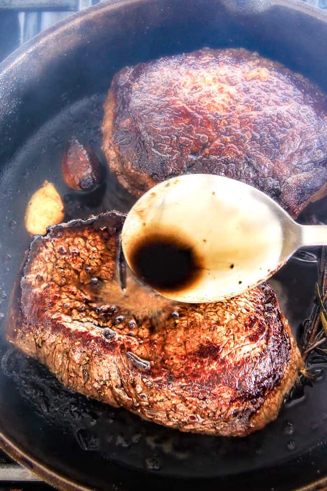 Showing how to baste Pan Seared Steak with Balsamic Herb Cream Sauce.