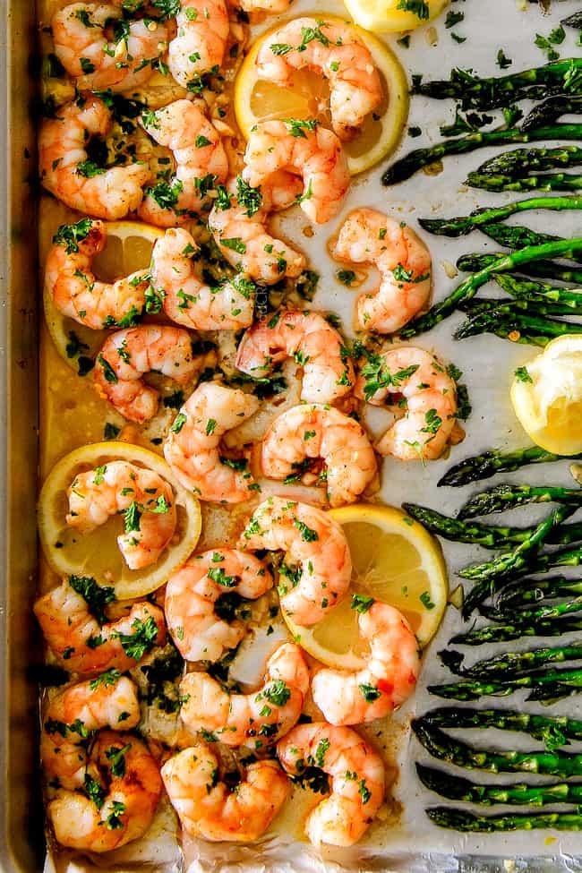 Close up of Roasted Lemon Garlic Butter Shrimp and Asparagus on a pan with lemon.