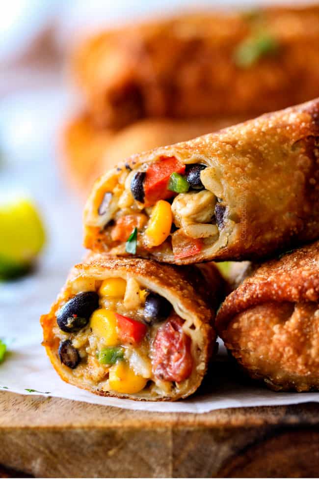 CRISPY Southwest Egg Rolls loaded with Mexican spiced chicken, beans, tomatoes, rice, avocado and cheese! These egg rolls are unreal! So much flavor and texture! And don't skip the Cilantro Lime Ranch Dip - its heaven! up close of open Southwest Egg Rolls oozing with cheesy filling with avocado, chicken, tomatoes, corn and black beans