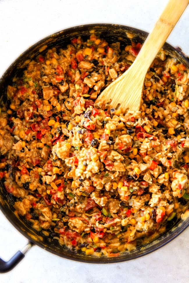 CRISPY Southwest Egg Rolls loaded with Mexican spiced chicken, beans, tomatoes, rice, avocado and cheese! These egg rolls are unreal! So much flavor and texture! And don't skip the Cilantro Lime Ranch Dip - its heaven! Showing how to make Southwest Egg Rolls by stirring cheese into chicken, black beans, avocados and tomatoes