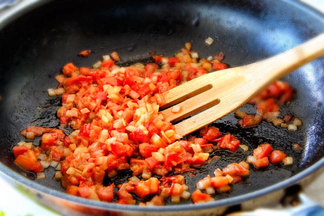 Showing how to make Garlic Mozzarella Margherita Pasta by cooking tomatoes in a pan.