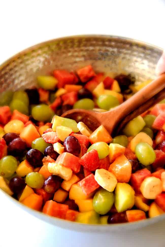 Watermelon Fruit Salad with Creamy Citrus Glaze - I took this to a barbecue and it was gone in minutes! Its so cool and refreshing withe the BEST GLAZE and I love the combo of melons, strawberries, bananas, apples and grapes! a wooden spoon in the best watermelon salad