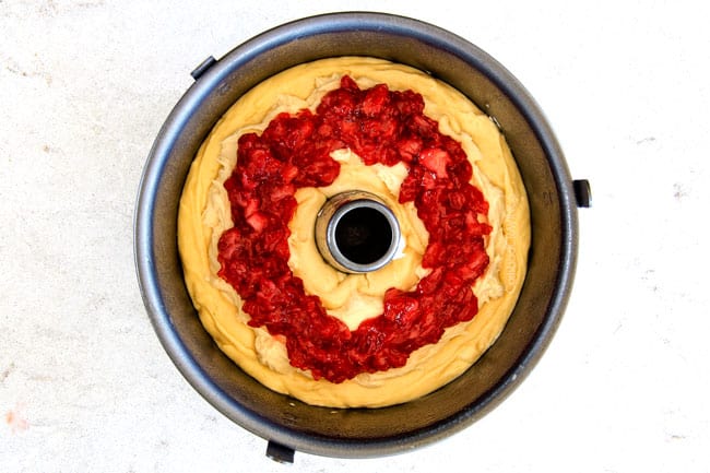 Strawberry Cream Cheese STUFFED Sour Cream Coffee Cake - this is the best strawberry coffee cake ever! the INCREDIBLY creamy cheesecake-like cream cheese filling and strawberries all topped with Coconut Pecan Streusel and Lemon Drizzle is OUT OF THIS WORLD! I can't say enough good things about this coffee cake! showing how to m make Cream Cheese Coffee Cake bu adding cream cheese on top of batter in a bundt pan