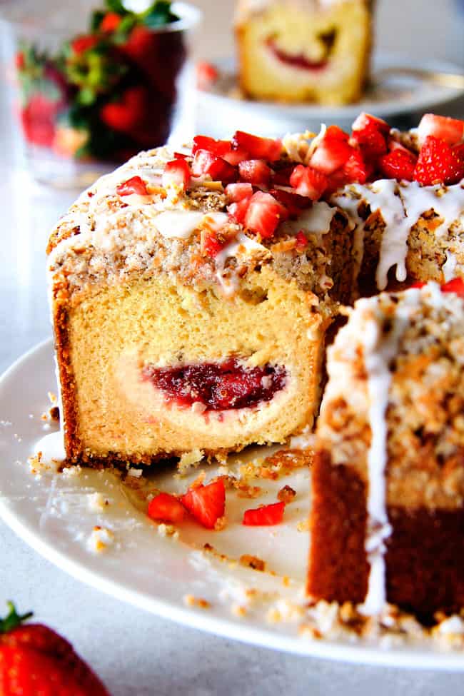 Strawberry Cream Cheese STUFFED Sour Cream Coffee Cake - this is the best strawberry coffee cake ever! the INCREDIBLY creamy cheesecake-like cream cheese filling and strawberries all topped with Coconut Pecan Streusel and Lemon Drizzle is OUT OF THIS WORLD! I can't say enough good things about this coffee cake! Strawberry Cream Cheese Cream Coffee Cake with a few slices missing on a white plate