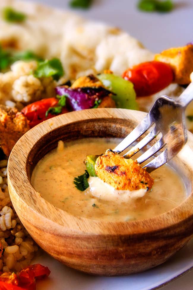 Tandoori Chicken Kabobs being dipped in sauce.