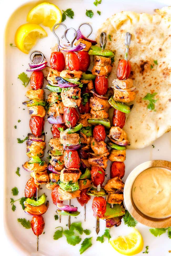 Tandoori Chicken Kabobs next to bread and dipping sauce.