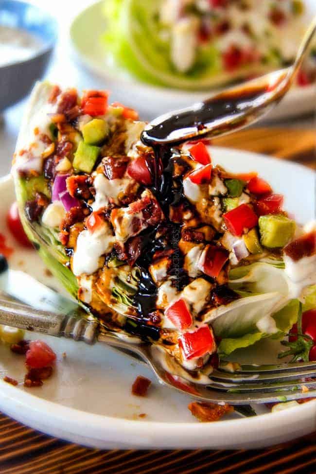 Outback Copycat Wedge Salad smothered in the most amazing creamy, decadent Blue Cheese Ranch and Balsamic Reduction is a flavor/texture lovers dream and crazy easy to make! showing how to eat wedge salad by smothering it with dressing