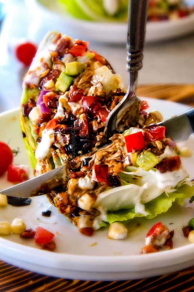 Outback Copycat Wedge Salad smothered in the most amazing creamy, decadent Blue Cheese Ranch and Balsamic Reduction is a flavor/texture lovers dream and crazy easy to make! showing how to eat Wedge Salad by cutting it with a knife and fork