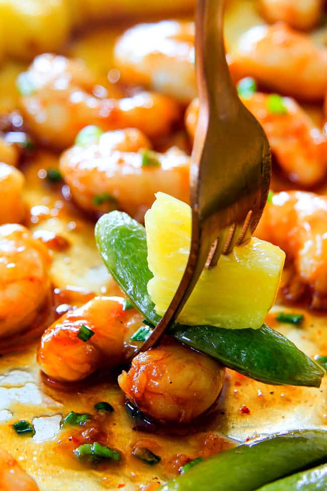 I am in love with this Sheet Pan Teriyaki Shrimp, Pineapple and Snap Peas! Its SO easy, healthy, a meal-in-one and the homemade Teriyaki sauce is the best I've ever had (DON'T be tempted to use store bought!)! I'm always keeping frozen shrimp on hand so I can make this any time! up close of a fork with teriyaki shrimp with the best homemade teriyaki sauce