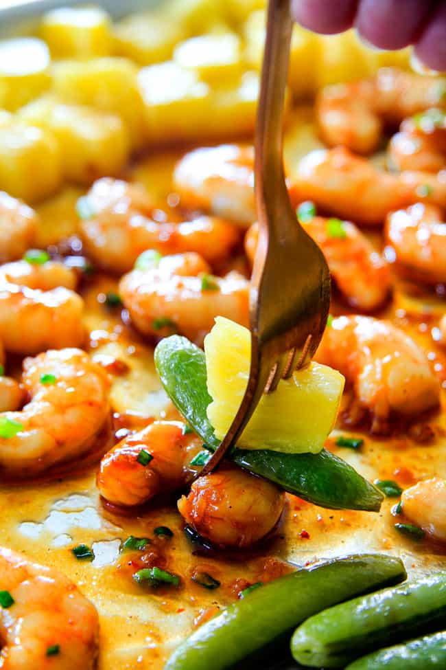 I am in love with this Sheet Pan Teriyaki Shrimp, Pineapple and Snap Peas! Its SO easy, healthy, a meal-in-one and the homemade Teriyaki sauce is the best I've ever had (DON'T be tempted to use store bought!)! I'm always keeping frozen shrimp on hand so I can make this any time! a fork taking a bite of teriyaki shrimp and pineapple