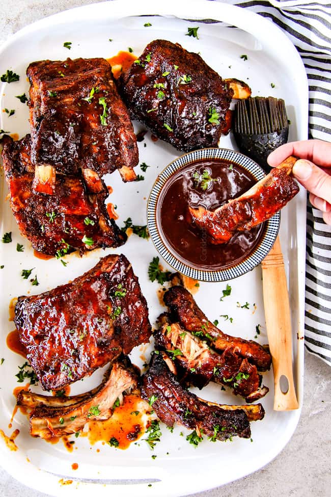 Dipping Slow Cooker Honey Buffalo Ribs in sauce.