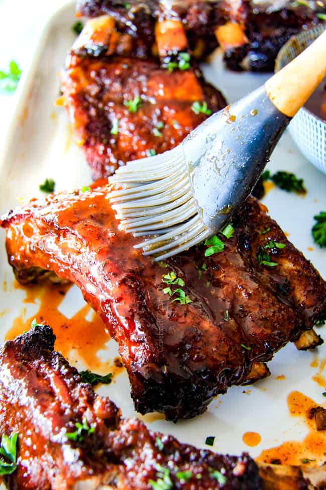 Brushing Slow Cooker Honey Buffalo Ribs with sauce.