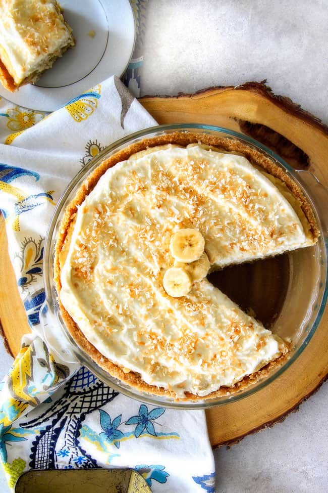 Banana Coconut Cream Pie in a pan with a slice missing.
