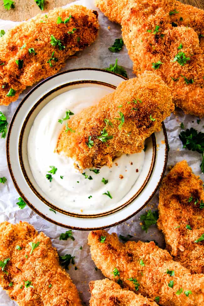 Baked Cheddar Ranch Chicken Tenders dipping in sauce.
