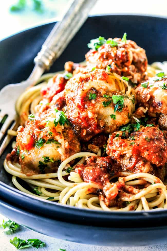 Side view of Italian Meatballs with pasta on a black plate.