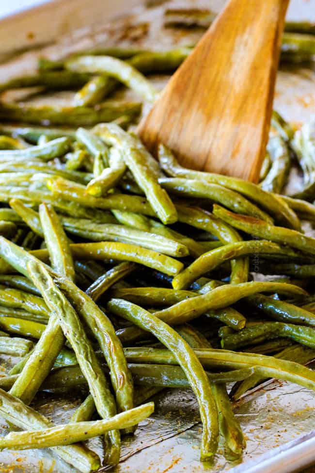 Forget green bean casserole, these wonderfully flavorful, crisp tender Roasted Green Beans with Creamy Gruyere Sauce are AMAZING!!! They the best green beans you will ever eat! They are easy enough for every day but delicious enough for special occasions (like Thanksgiving, Christmas!)! #greenbeancasserole #thanksgivingrecipe showing how to cook green beans by stirring them halfway through baking
