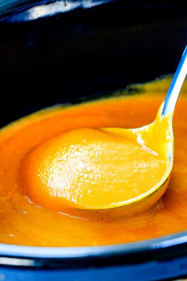 this SUPER creamy Slow Cooker Chipotle Sweet Potato Soup is AMAZING! Its loaded with flavor, gluten free, dairy free, crazy healthy and so easy! Definitely one of my new favorite soups! up close of a ladle of full of savory sweet potato soup