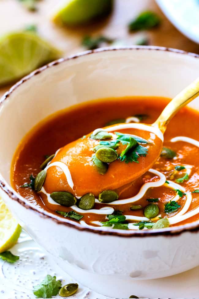 this SUPER creamy Slow Cooker Chipotle Sweet Potato Soup is AMAZING! Its loaded with flavor, gluten free, dairy free, crazy healthy and so easy! Definitely one of my new favorite soups! a spoon taking a bite of best sweet potato soup