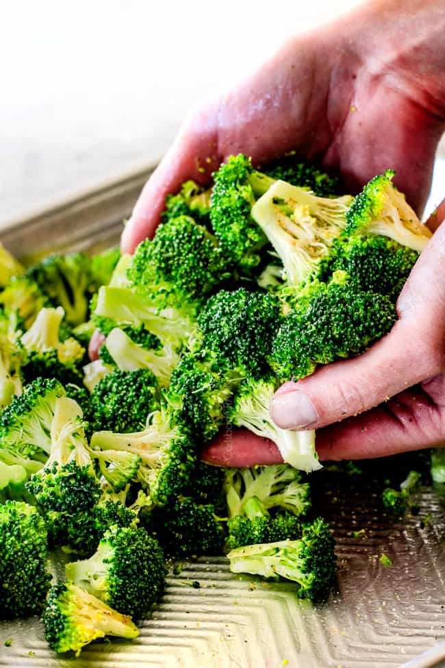 QUICK AND EASY this Parmesan Roasted Broccoli is bursting with flavor, caramelized crispy tops and the quickest side dish to every meal all made in ONE PAN! AKA Minimal effort, HUGE flavor! showing how to roast broccoli by tossing broccoli with olive oil on a baking sheete