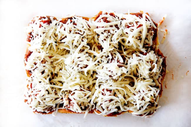 These Cheesy Italian Meatball Sliders are my favorite party food ever and my family loves them for dinner! The meatballs are the BEST (so tender and juicy!) and the marinara is amazing and I love how they are individual sliders instead of meatball subs! I can't recommend these enough! showing how to make meatball sliders by topping meatballs with cheese