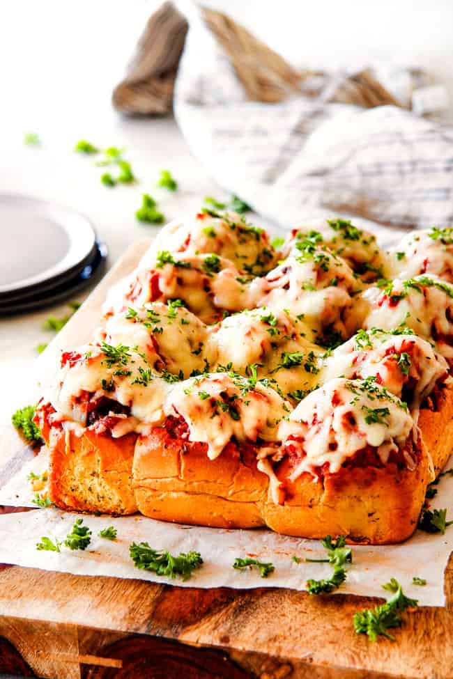 These Cheesy Italian Meatball Sliders are my favorite party food ever and my family loves them for dinner! The meatballs are the BEST (so tender and juicy!) and the marinara is amazing and I love how they are individual sliders instead of meatball subs! I can't recommend these enough! far away view of meatball sliders on Hawaiian buns