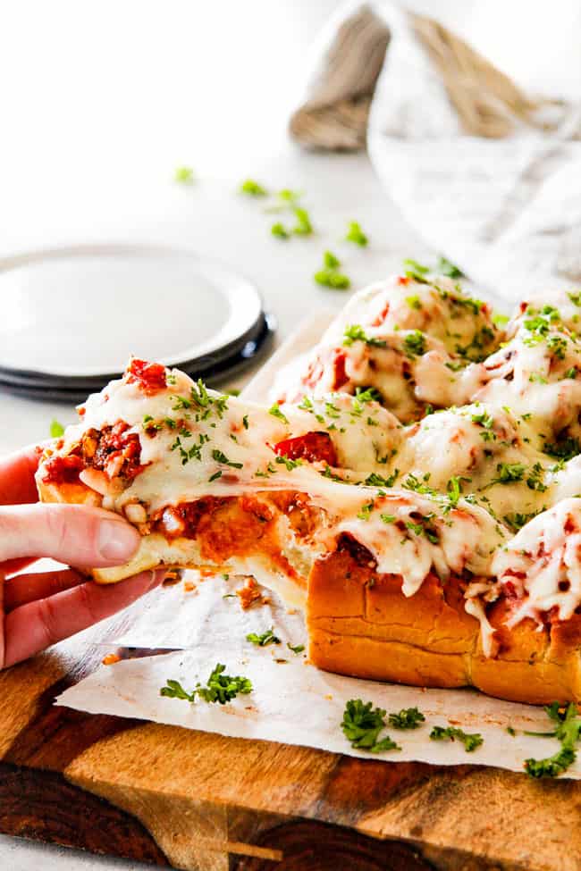 These Cheesy Italian Meatball Sliders are my favorite party food ever and my family loves them for dinner! The meatballs are the BEST (so tender and juicy!) and the marinara is amazing and I love how they are individual sliders instead of meatball subs! I can't recommend these enough! pulling a meatball slider away from the tray with a string of goeey mozzarella cheese