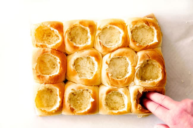 These Cheesy Italian Meatball Sliders are my favorite party food ever and my family loves them for dinner! The meatballs are the BEST (so tender and juicy!) and the marinara is amazing and I love how they are individual sliders instead of meatball subs! I can't recommend these enough! showing how to make meatball sliders by hollowing out Hawaiian rolls