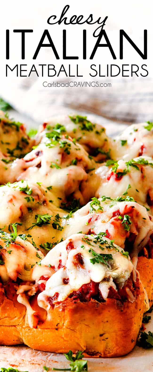 These Cheesy Italian Meatball Sliders are my favorite party food ever and my family loves them for dinner! The meatballs are the BEST (so tender and juicy!) and the marinara is amazing and I love how they are individual sliders instead of meatball subs! I can't recommend these enough! up close of meatball slider with mozzarella cheese and marinara sauce