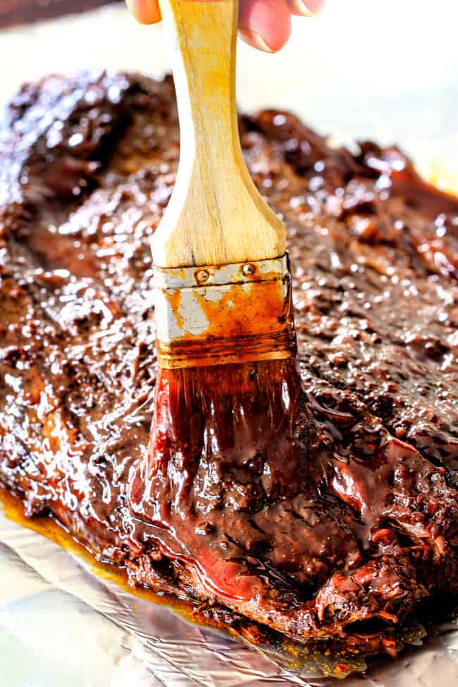 brushing bbq sauce onto piece of slow cooker brisket