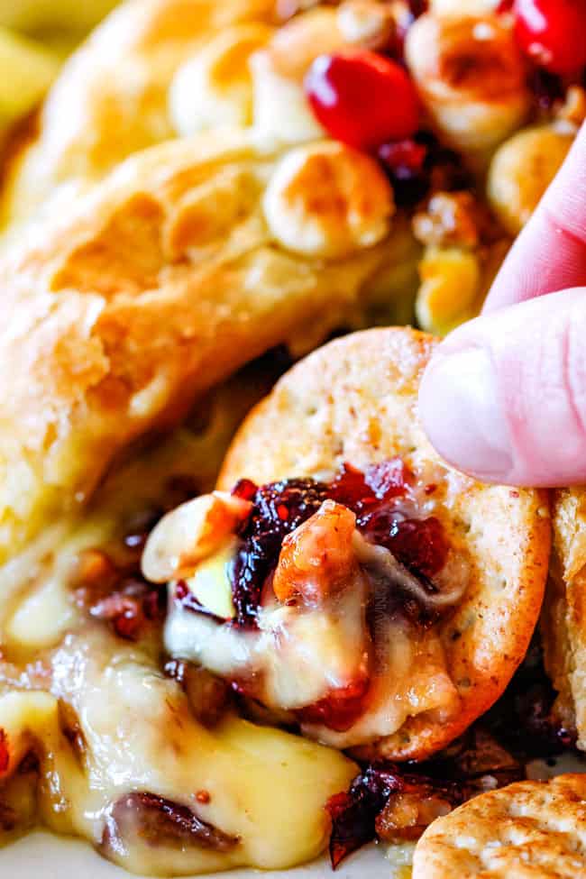 Rich and creamy Baked Brie in Puff Pastry is always a total luxuriously tasting crowd pleaser with minimal effort! (step by step pictures included) It can be prepped in advance then baked when you're ready for company! up close of oozing baked brie in puff pastry with jam, cranberries and pecans