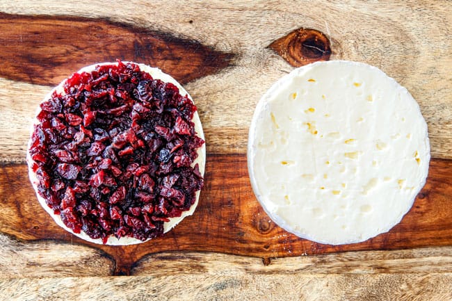 Rich and creamy Baked Brie in Puff Pastry is always a total luxuriously tasting crowd pleaser with minimal effort! (step by step pictures included) It can be prepped in advance then baked when you're ready for company! aaaaaaaaa showing how to make baked brie in puff pastry by adding jam and cranberries to one half of brie