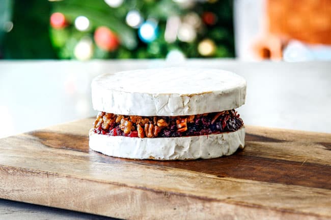 Rich and creamy Baked Brie in Puff Pastry is always a total luxuriously tasting crowd pleaser with minimal effort! (step by step pictures included) It can be prepped in advance then baked when you're ready for company! aaaaaaaaa showing how to make baked brie in puff pastry by assembling top and bottom of brie with jam filling in the middle