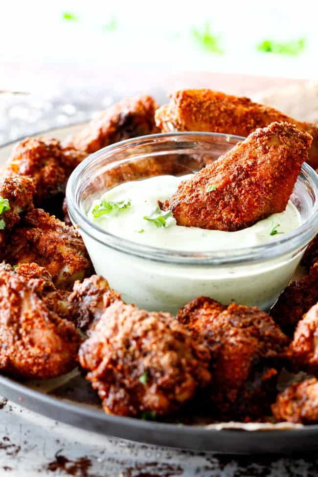 Ancho Baked Chicken Wings dipping in a cup of sauce.