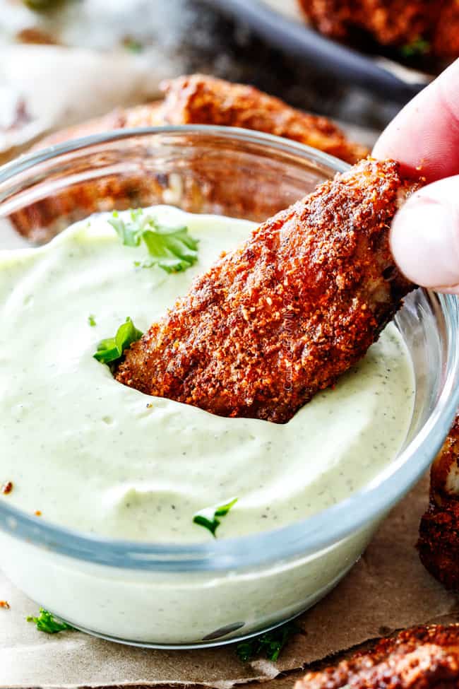 Dipping a single Ancho Baked Chicken Wings in sauce.