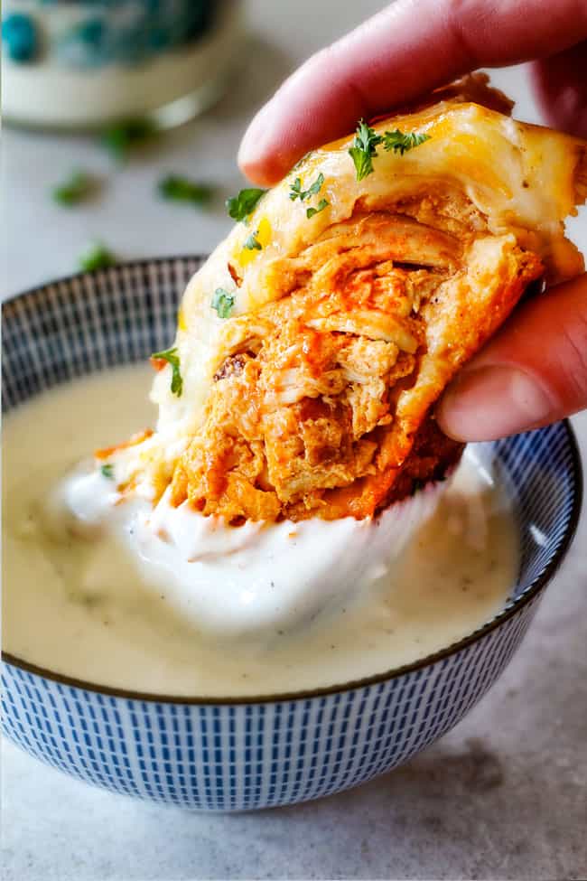 Mega flavorful Buffalo Chicken Pull Apart Bread is your favorite decadent creamy, cheesy dip baked right into a buttery biscuit ring! Crazy delicious EASY crowd pleasing appetizer perfect for parties or game day! It may look super impressive but you won’t believe how easy it is! up close of Buffalo Chicken Pull Apart Bread in a bowl of ranch