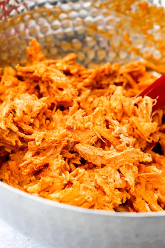 Mega flavorful Buffalo Chicken Pull Apart Bread is your favorite decadent creamy, cheesy dip baked right into a buttery biscuit ring! Crazy delicious EASY crowd pleasing appetizer perfect for parties or game day! It may look super impressive but you won’t believe how easy it is! showing how to make Buffalo Chicken Pull Apart Bread by mixing buffalo chicken, cream cheese and bacon together