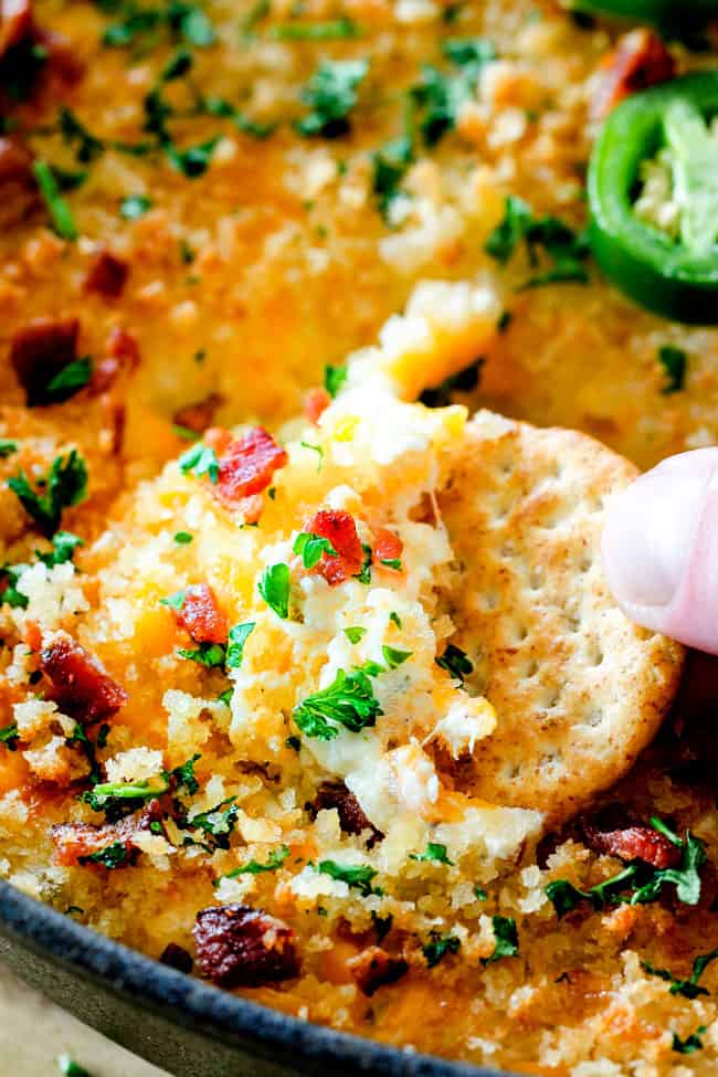 Ritz Cracker scooping into Best Jalapeno Popper dip with sour cream, mayonnaise and bacon