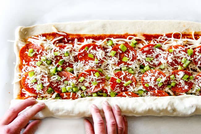 These Pizza Pinwheels are super easy to make, customizable, freeze beautifully, and absolutely irresistible for snacks, appetizers or fun meals! You friends and family will beg you to make these! showing how to make Pizza Pinwheels by rolling up dough