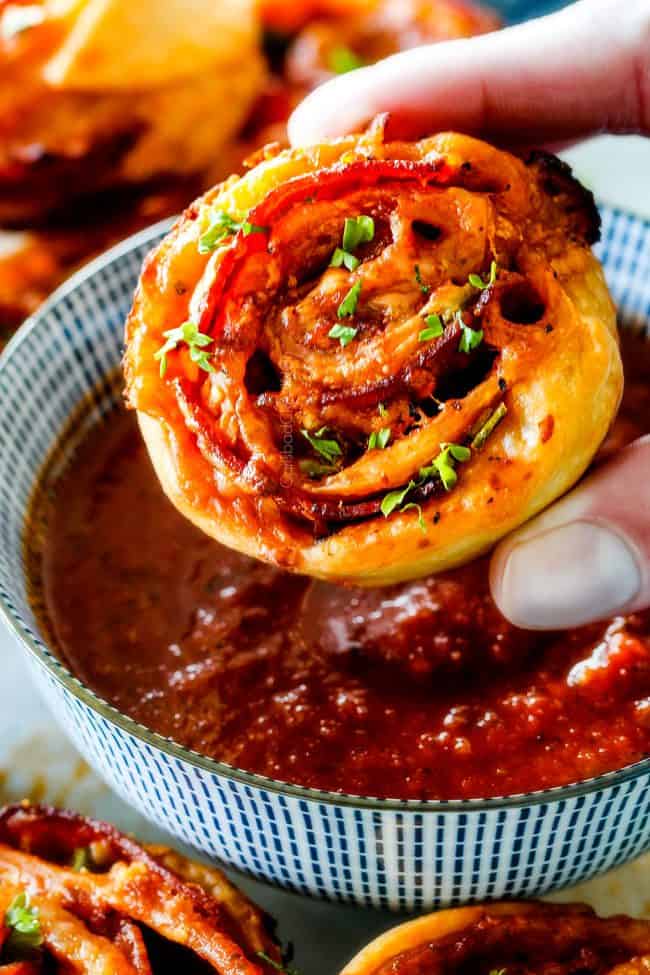 These Pizza Pinwheels are super easy to make, customizable, freeze beautifully, and absolutely irresistible for snacks, appetizers or fun meals! You friends and family will beg you to make these! dipping pizza pinwheel in marinara sauce