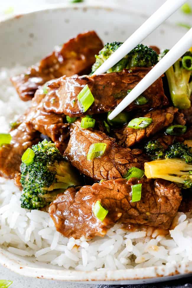 side view of beef broccoli with chopsticks picking up a piece of tender beef