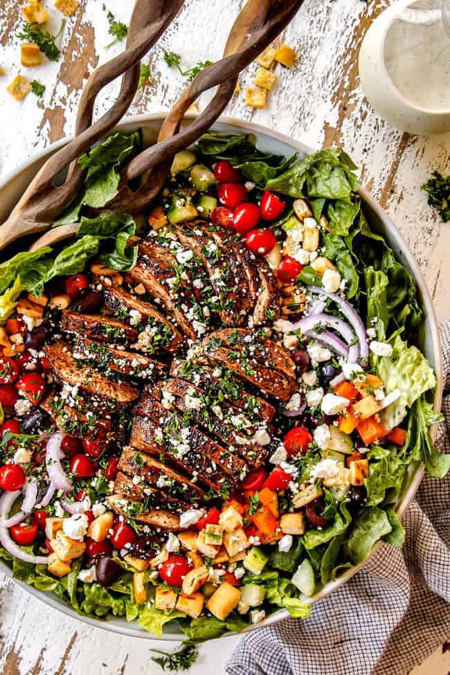 top view of Greek Chicken Salad with yogurt dressing in a white bowl with tomatoes, olives, cucumber, red onions and Greek Chicken