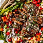 top view of Greek Chicken Salad with yogurt dressing in a white bowl with tomatoes, olives, cucumber, red onions and Greek Chicken