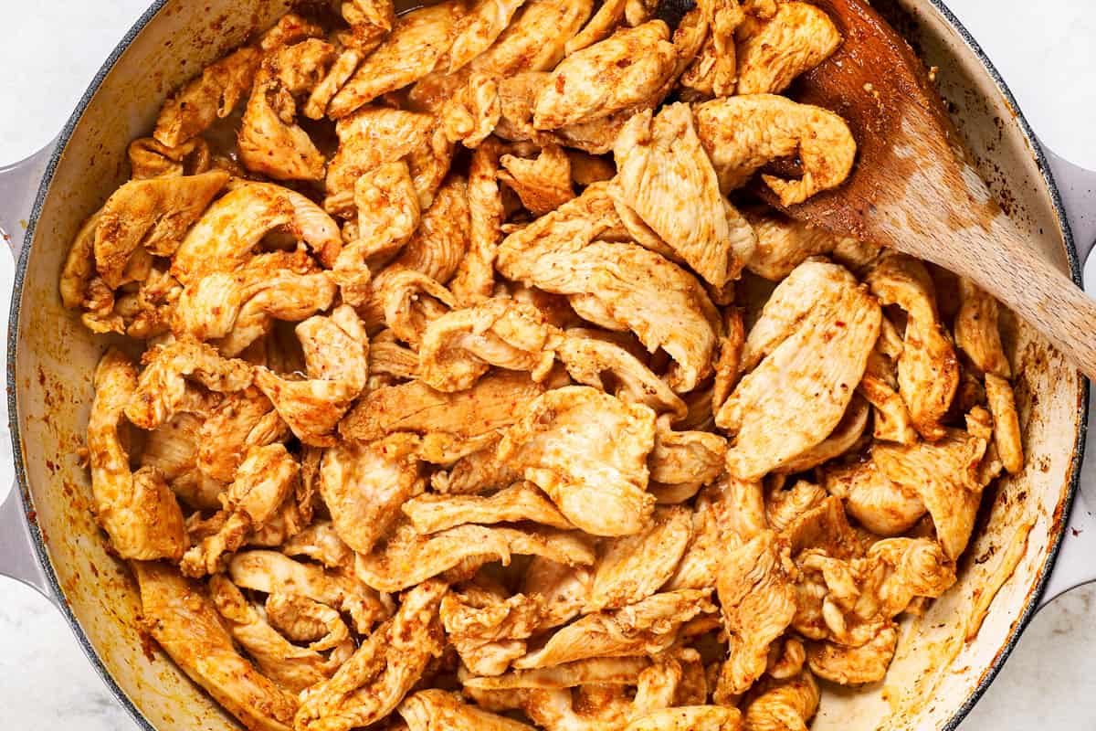 showing how to make panang curry by stir frying chicken in the panang curry paste