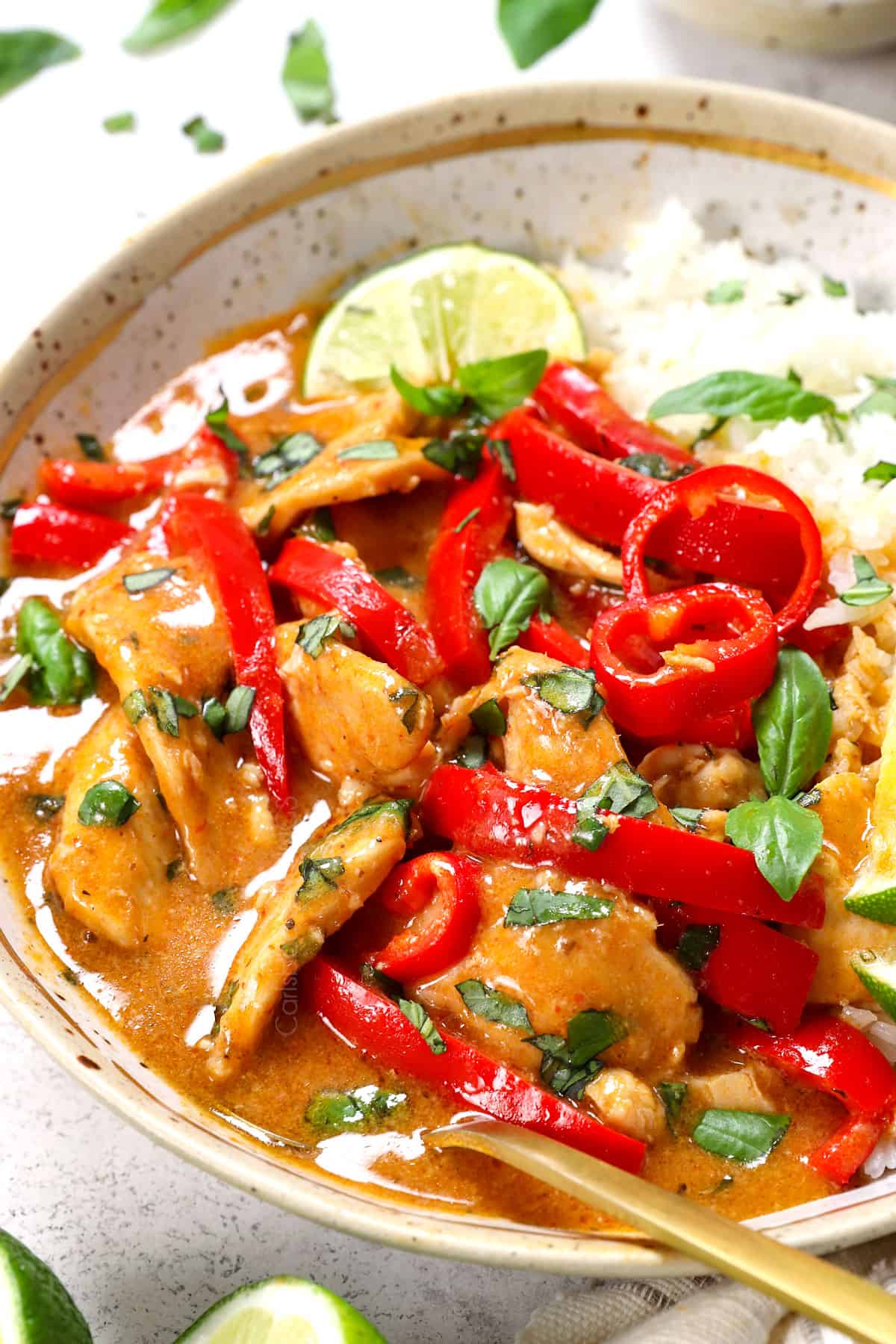 showing how to serve panang in a bowl with rice garnished with basil and chilies