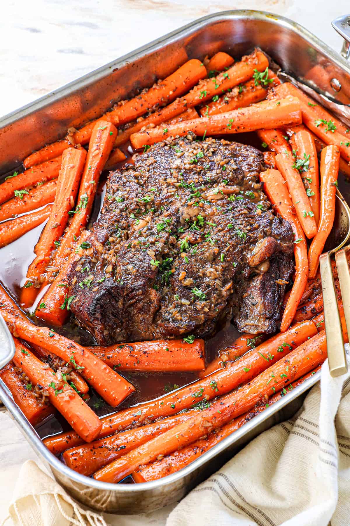 roast surrounded by carrots in a roasting pan
